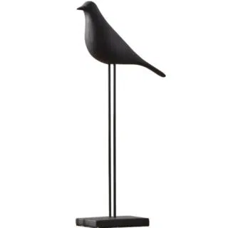 On voit, sur fond blanc, une statue d'oiseau noire, sur pied.