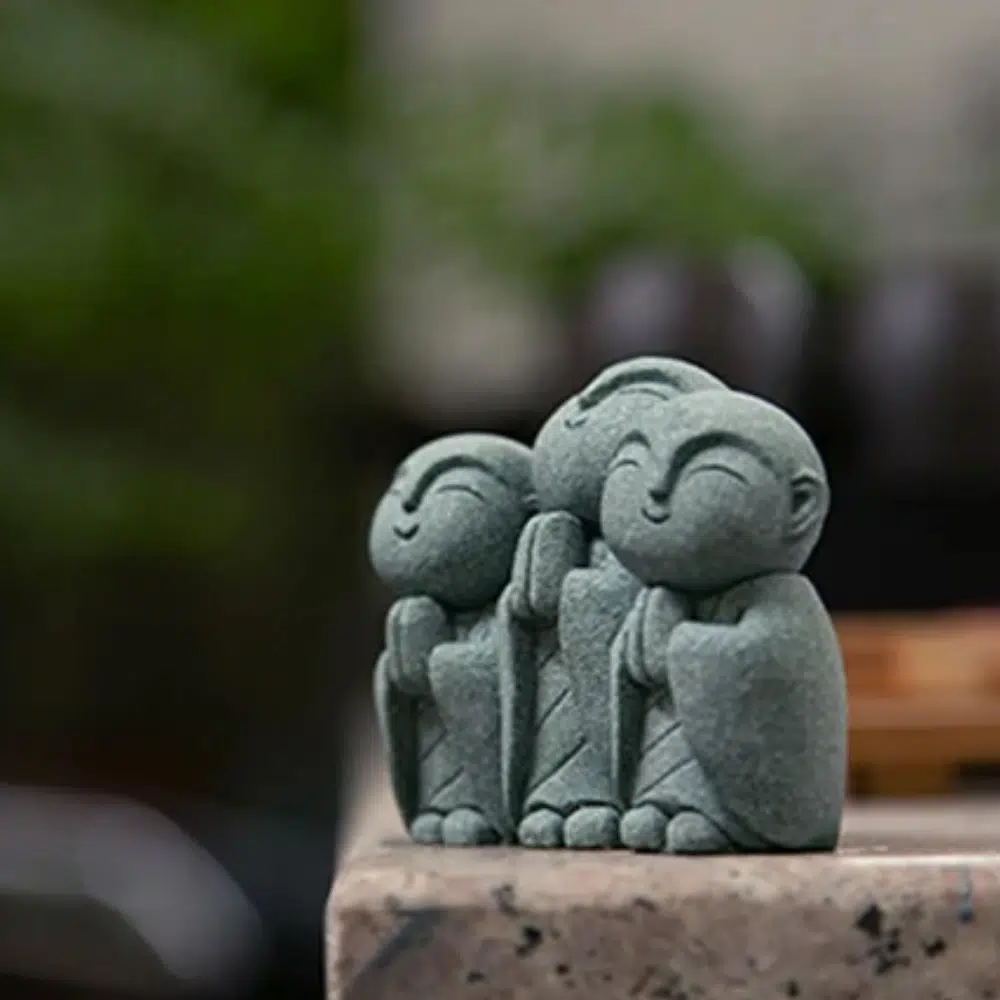 Statue de Jizo de 3 moines posé sur un rebord en pierre.
