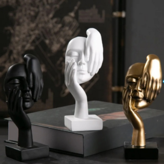 3 statues de visage (blanc, noir, doré) porté par une main et caressé par une autre main