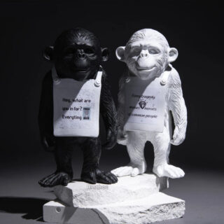 Statues de singes noire et blanche sur un fond noir.