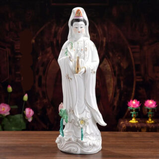 Photo d'une statue de bouddha blanche en porcelaine avec des fleurs colorées sur le piédestal le tout sur fond noir