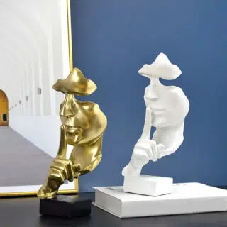 2 statues, blanche et or, de visage avec l'indexe posé sur le menton