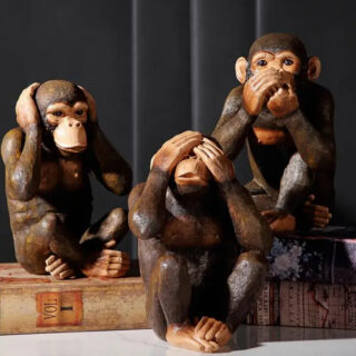 Trio de statues de singes de la sagesse posés sur un meuble.