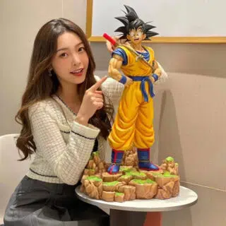 Statue Dragon Ball Z Goku pose à côté d'une femme asiatique