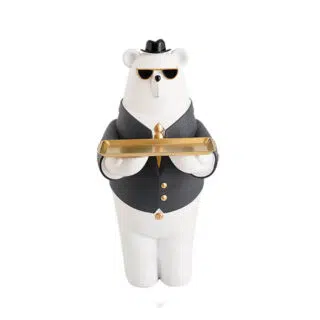 On voit une statue d'ours polaire blanc. Il est habillé en serveur avec une veste noire et il porte un plateau doré.