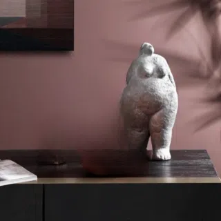 Statue d'une grosse femme debout en materiaux blanc sur un meuble marron