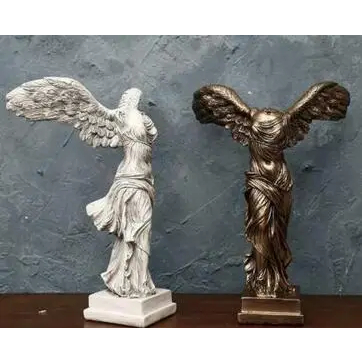 Photo représentant deux statues de la victoire de Samothrace l'une blanche l'autre couleur bronze sur fond bleu