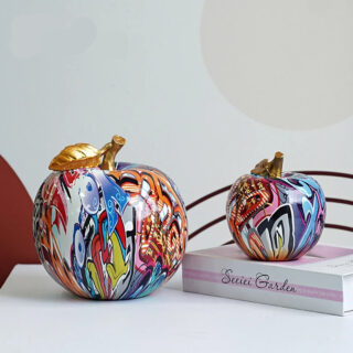 Statue pop art pomme, une grande et une plus petite sur un livre.