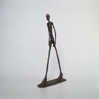 Statue d'homme mince sur un fond gris.
