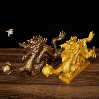 Photo de deux dragons sur socle un bronze et un doré avec boule dans une patte posés sur un meuble en bois