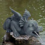 Photographie d'un bébé dragon ailé accroupi sur une pierre sur un bassin et crachant de l'eau