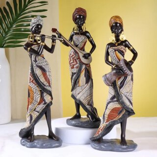 Photo de trois statues africaines représentant des musiciennes en robes et parées de bijoux en train de jouer sur un fond jaune