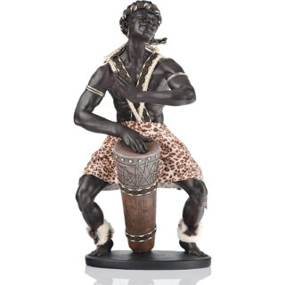 Photo d'une statue africaine représentant un musicien noir en pagne à bretelles croisées accroupi pour jouer du tambour avec de la fourrure blanche autour des chevilles et des boucles d'oreilles ainsi qu'un turban assorti