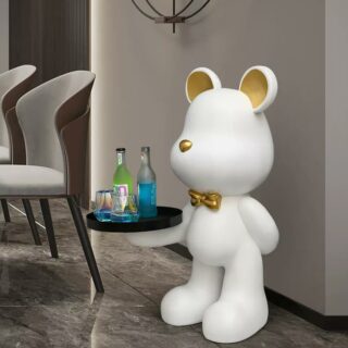 On voit une statue ours blanche qui porte un plateau noir. Il est dans une salle à manger moderne et grise.