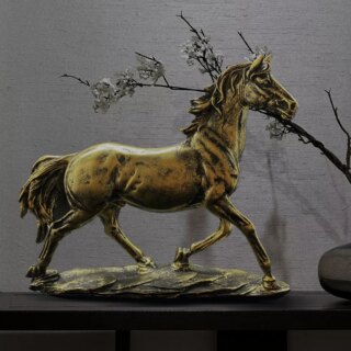 Petite statue de cheval au trop posé sur un meuble, fond gris.