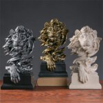 3 statue de tête de lion (doré, argenté et beige) avec une patte devant.