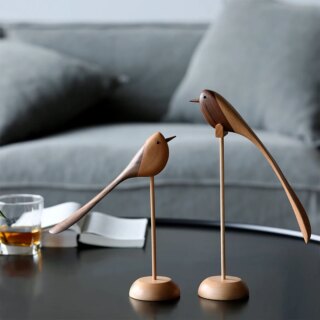 Sur une table de salon noire, on voit deux statues d'oiseau en bois une grande et une plus petite.