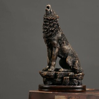 Statue de loup assis et hurlant sur un socle.