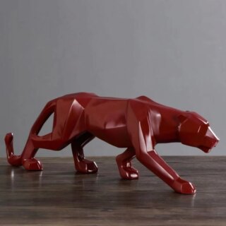 On voit une statue de panthère rouge sur un meuble en bois foncé.