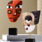 2 statues de visage (orange, blanc et marron)