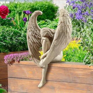 Statue d'ange posée sur un rebord en bois. Fond végétal.