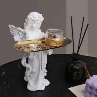 Statue d'ange portant un plateau doré et posé sur une table noire.