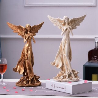 On voit deux statues d'ange posées sur une table.