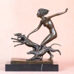 Photo d'une statue en bronze d'Artémis nue courant avec ses chiens sur socle de marbre et fond rose