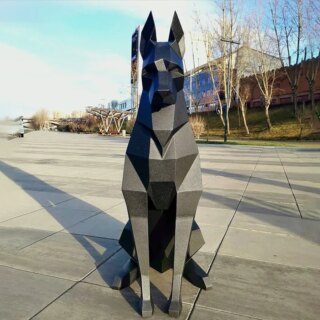 Statue origami chien en papier noir posé sur le sol dans la rue