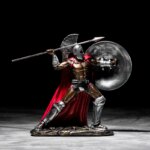 Photo d'une statue romaine représentant Spartacus en armure argentée et cape rouge javelot à la main prêt à lancer le tout sur fond noir