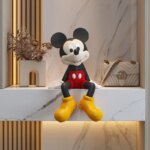 On voit une statue de Mickey d'une trentaine de centimètres de haut qui est assis sur le bord d'une étagère en marbre.
