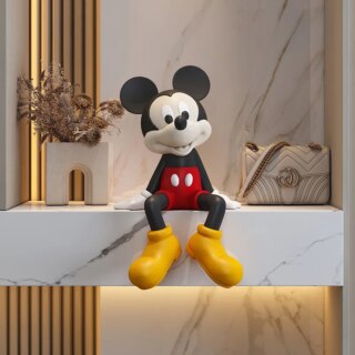 On voit une statue de Mickey d'une trentaine de centimètres de haut qui est assis sur le bord d'une étagère en marbre.