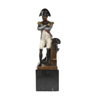Photo d'une statue de Napoléon Bonaparte debout les bras croisés en costume d'apparat sur son socle en marbre le tout sur fond blanc