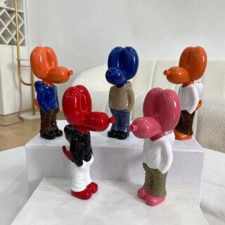 Statues street art chiens ballon de différentes couleurs posées sur une table à deux niveaux