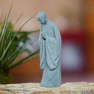 Statue grise de moine debout la tête baissée