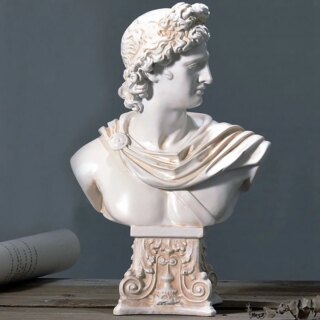 Photo d'un buste d'Apollon blanc avec un tissu plissé sur les épaules un bandeau fin dans les cheveux bouclés le tout sur fond gris piédestalouvragé