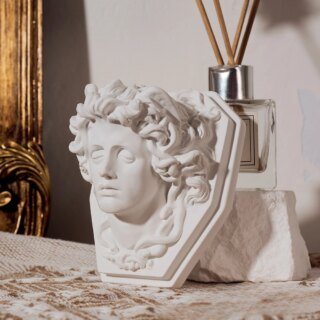 Statue de Medusa sur un socle et posée sur un meuble.
