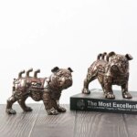 Deux statues industrielles Bouledogue en engrenages, une sur un livre et l'autre sur la table.