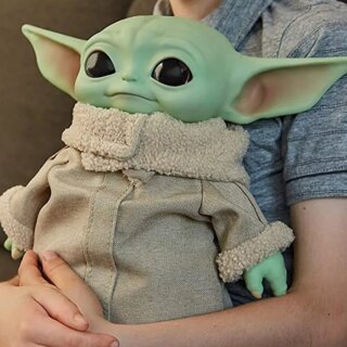 Statue star wars yoda tenue dans les bras d'une personne.
