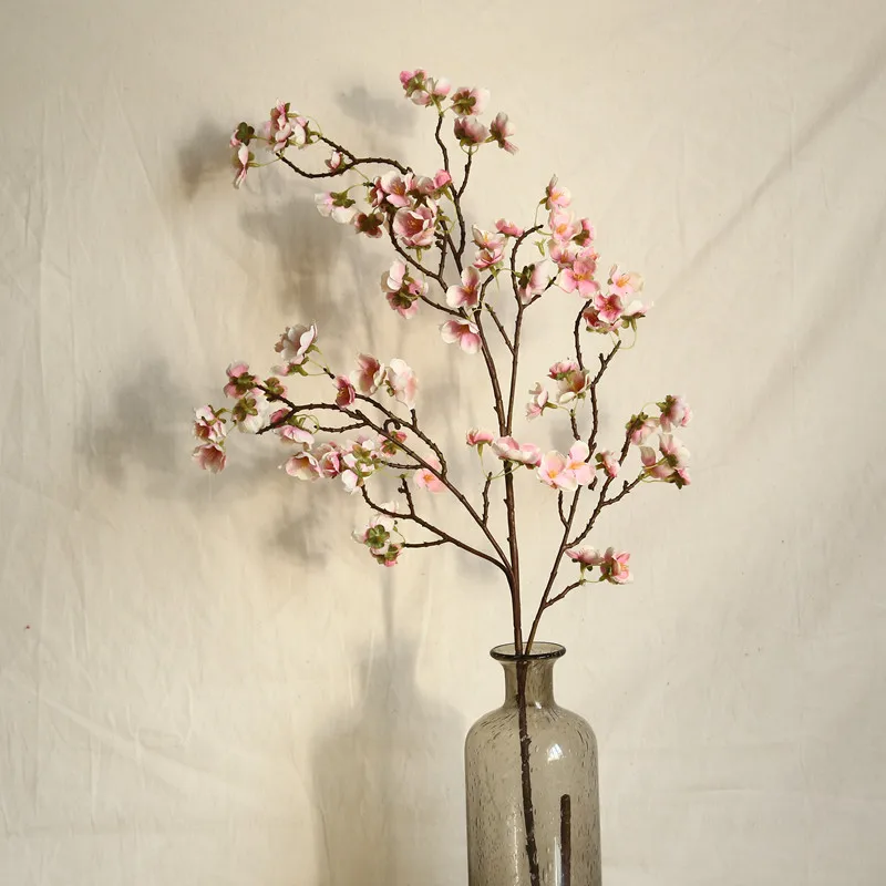 Branche de fleurs artificielles dans un vase transparent