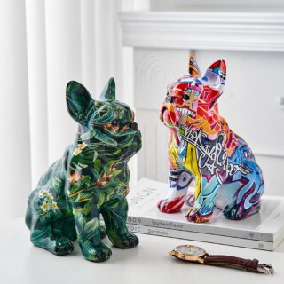 On voit deux statues de chien type Bouledogue. La première est verte avec des motifs et la seconde comme taguée de grafitis multicolores modernes. Les deux sont présentées sur fond blanc près d'une montre.