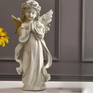 Statue d'un ange en robe blanche et aile déployées. L'ange est en prière