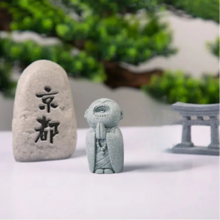 Petite statue gris d'un moine la bouche grande ouverte, les mains jointes sous le menton